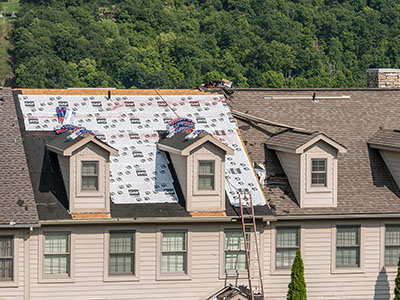 Large residential building getting new brown GAF shingles installed