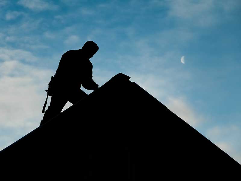 Silhouette of a worker on a residential roof